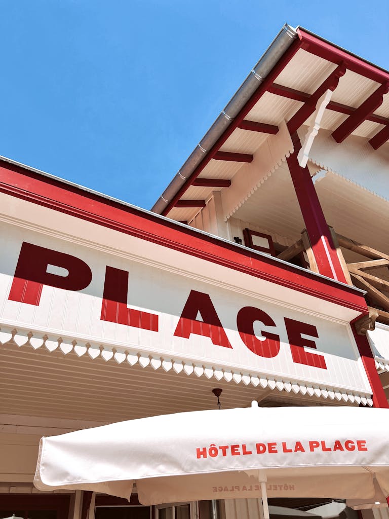 Low angle shot of a beach hotel with bold red and white signage in bright sunlight.